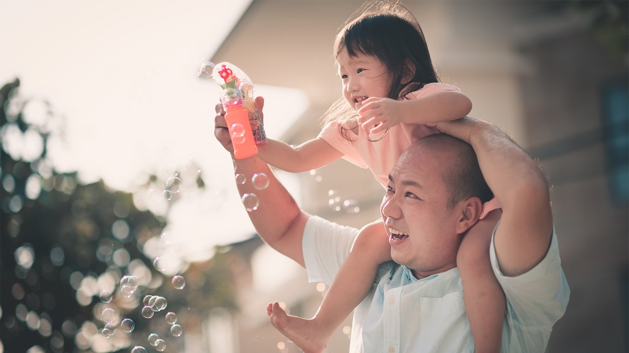 Mother and son blowing bubbles in the park; the image used for build emergency savings