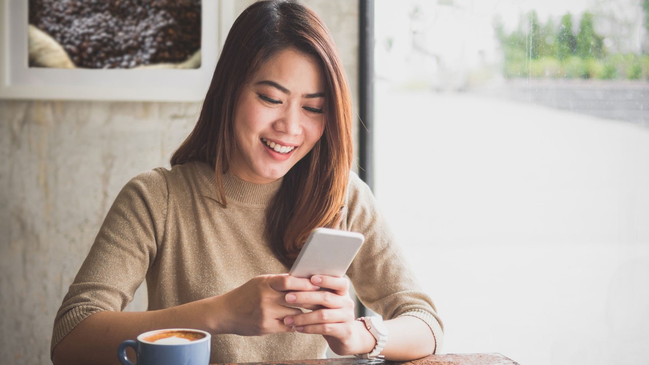 Girl looking at mobile phone in coffee shop; the image used for live within your means